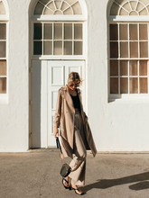 a lady wears a beige trenchcoat with matching pants